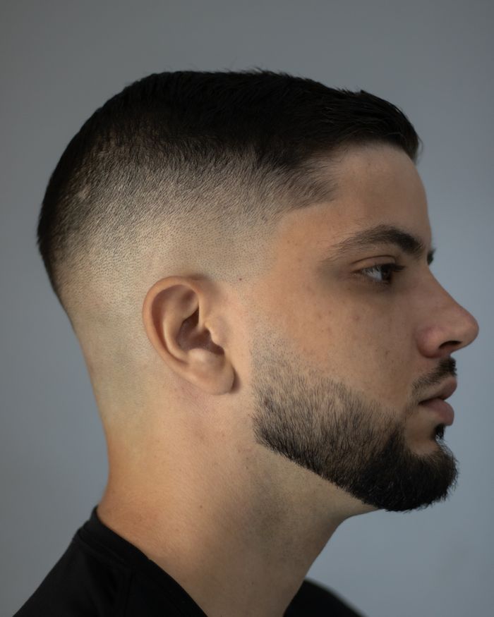 High skin fade met baard Zijaanzicht van een man met een high skin fade en een kort getrimde baard