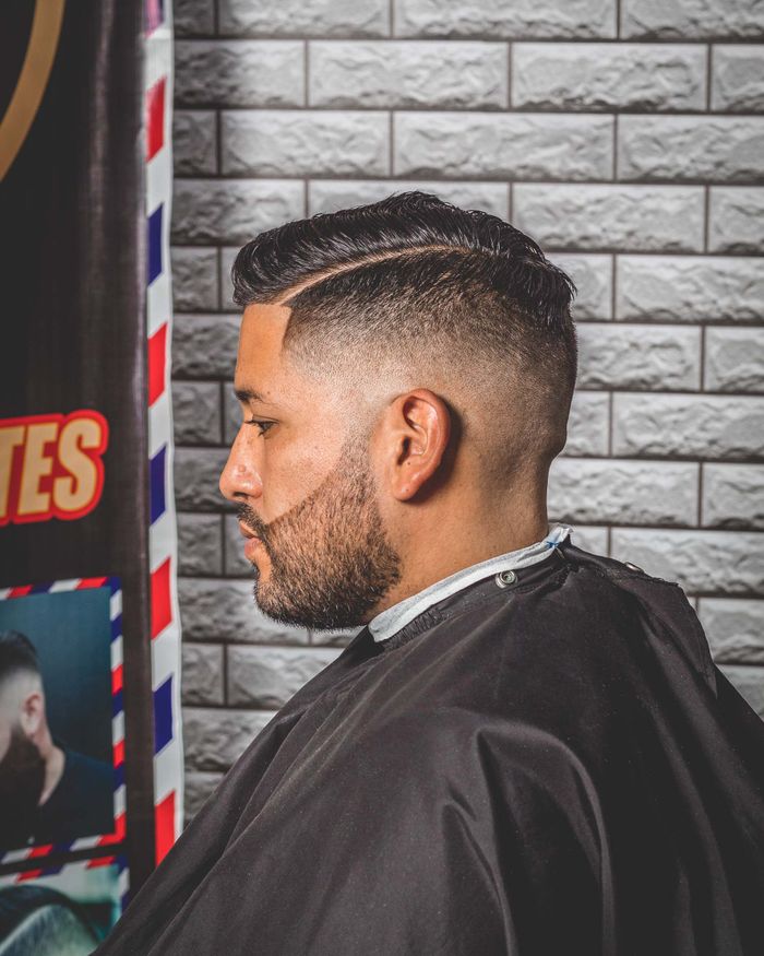 Mid fade met harde scheiding Man met een mid fade en een geschoren scheiding in de barbershop