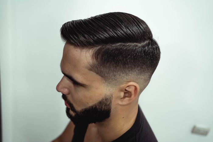 Fade met side part Man met langer haar bovenop in een side part en een fade aan de zijkant